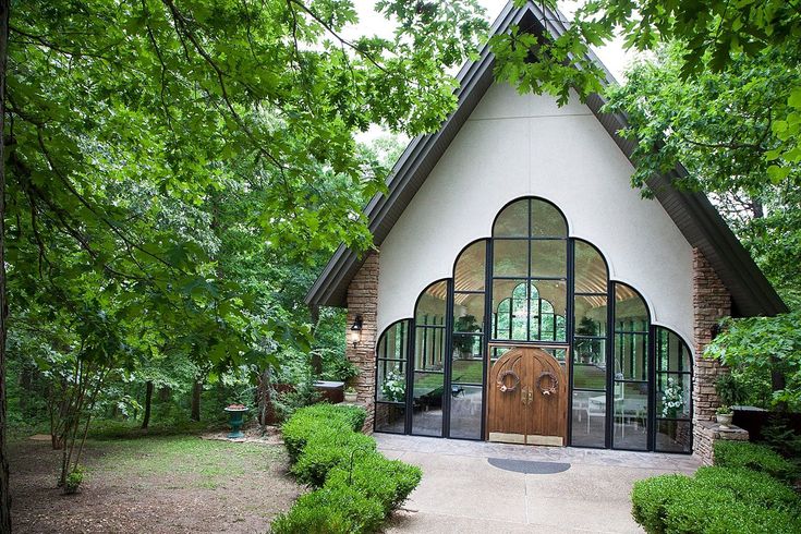 a white house with a brown door surrounded by trees