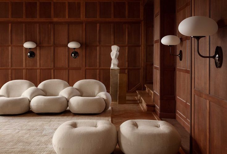 a living room with wooden paneling and white furniture on the floor in front of two lamps