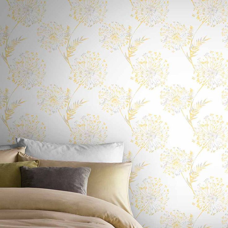 a bed sitting under a yellow wallpaper next to a white and gray headboard