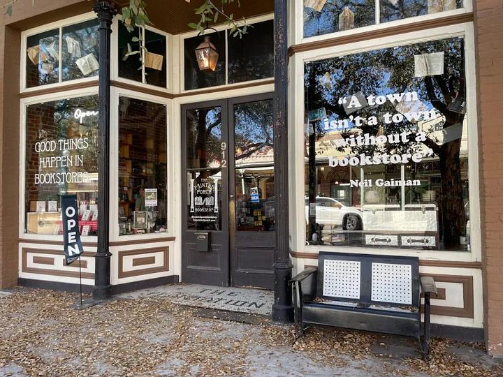 a storefront with two benches in front of it and the windows are decorated with signs