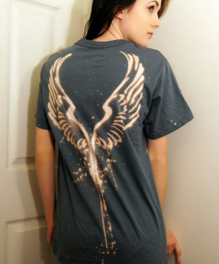 a woman standing in front of a door wearing a t - shirt with wings on it