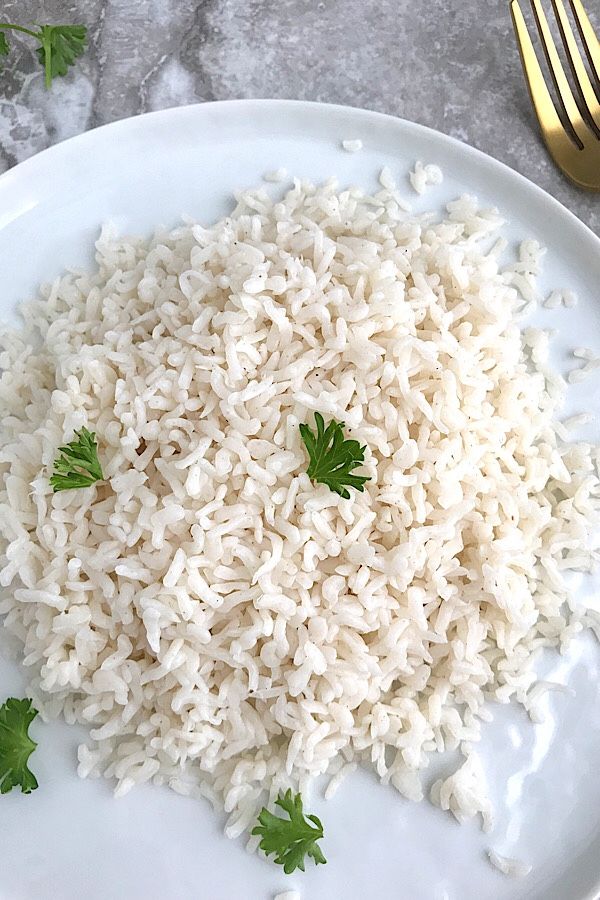 a white plate topped with rice and garnished with parsley next to a fork