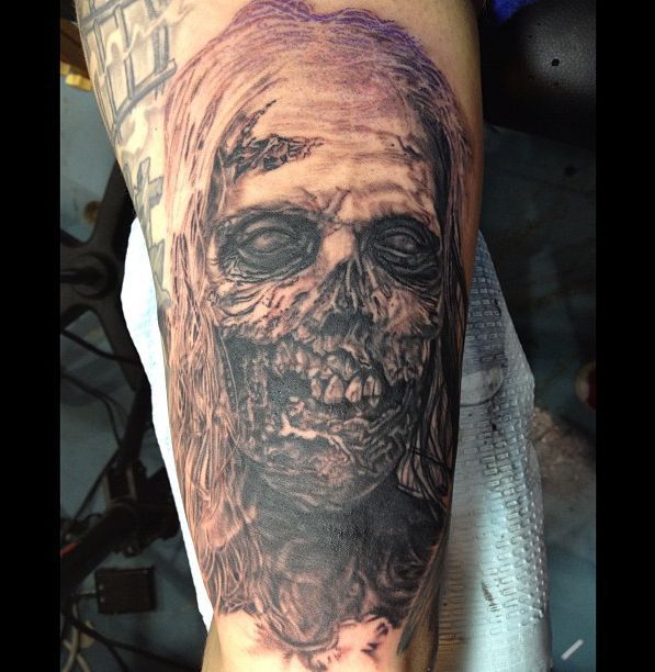 a man's arm with a black and grey tattoo on it that has an image of a zombie