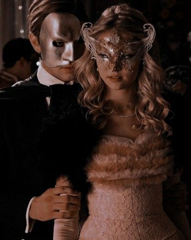 a man and woman dressed up in costume standing next to each other with masks on their faces