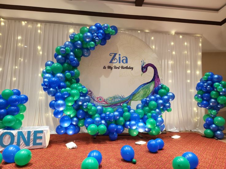 blue and green balloons in the shape of peacocks on display at a birthday party