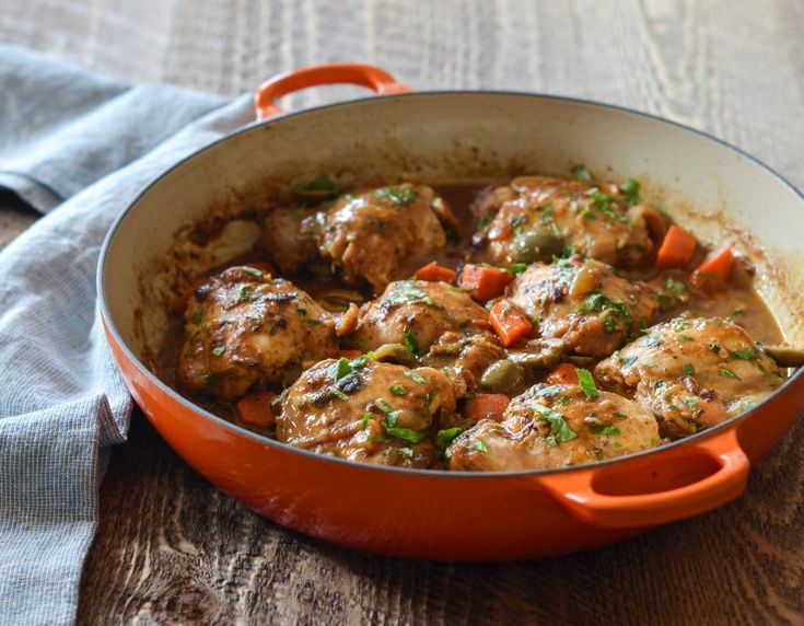 a pan filled with meat and vegetables on top of a wooden table