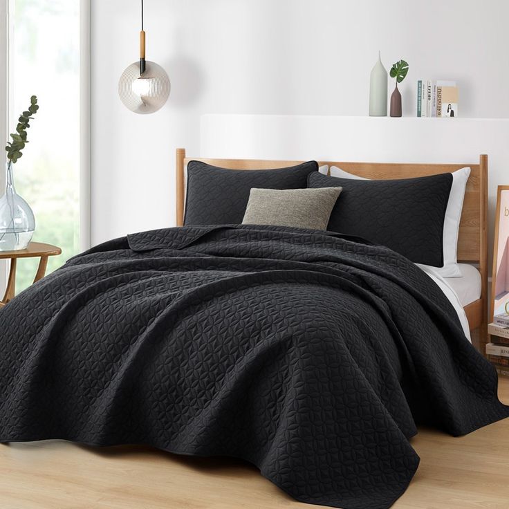 a bed with black bedspread and pillows in a room