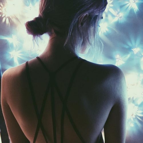 the back of a woman's bra with blue lights behind her