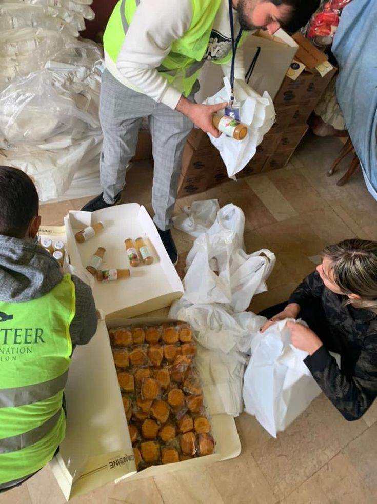 some people are standing around boxes with food in them