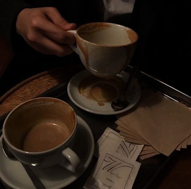 two cups of coffee sitting on top of a table next to papers and napkins