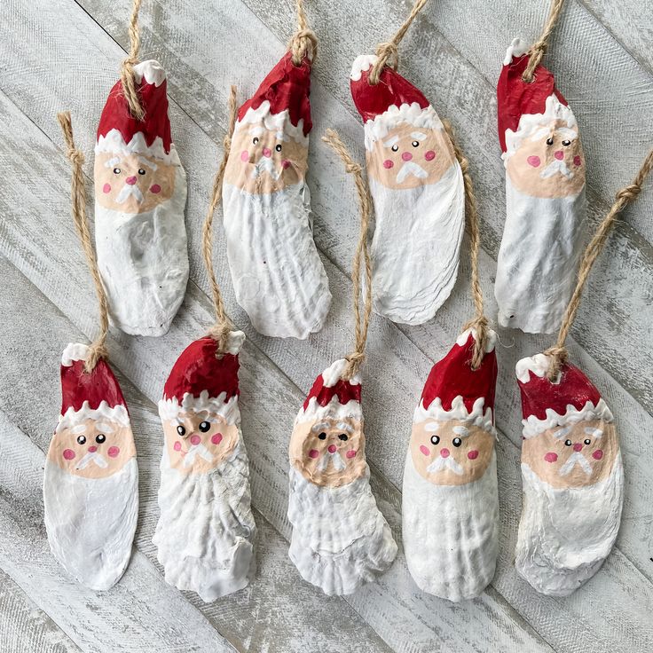 six santa claus ornaments hanging from twine strings on a white wooden table with rope