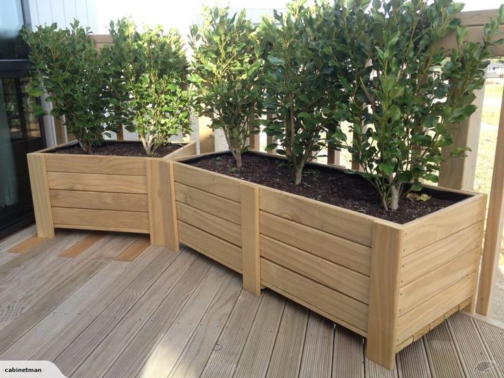 three wooden planters with trees in them on a deck