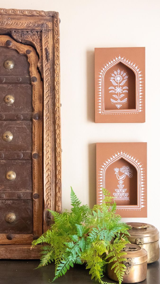 there are two framed pictures on the wall next to a potted plant and a mirror