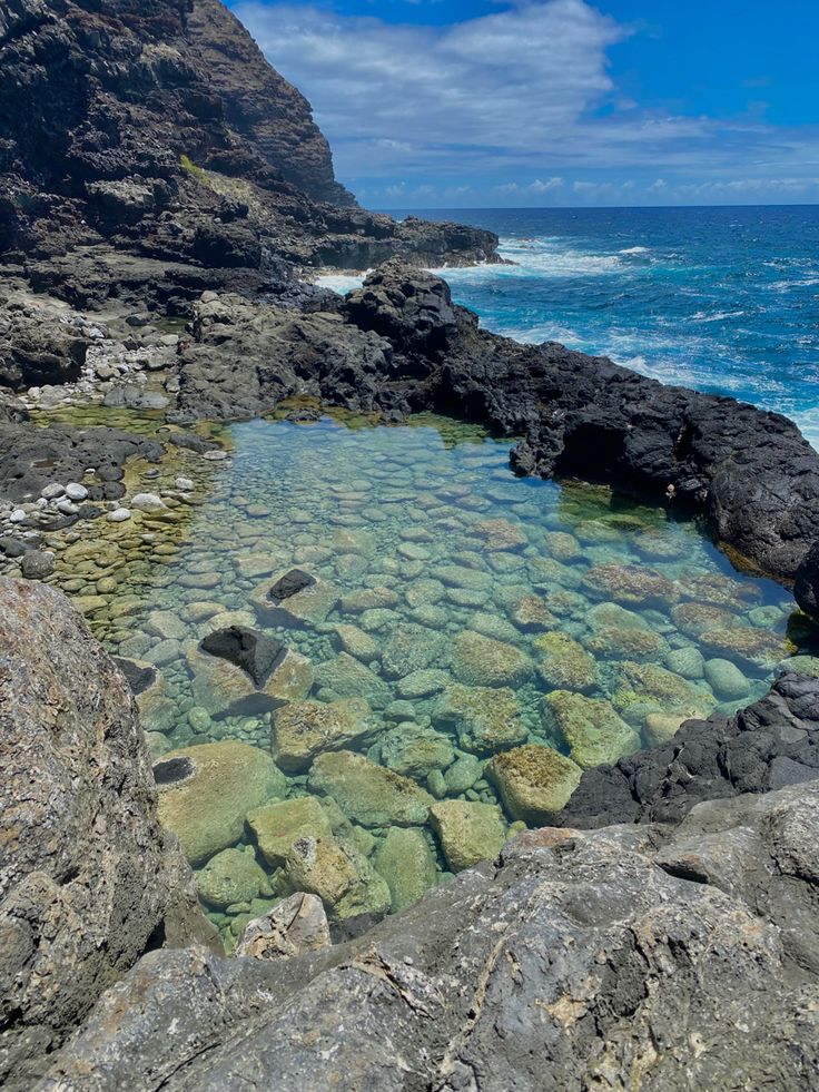 clear blue water surrounded by rocks on the beach