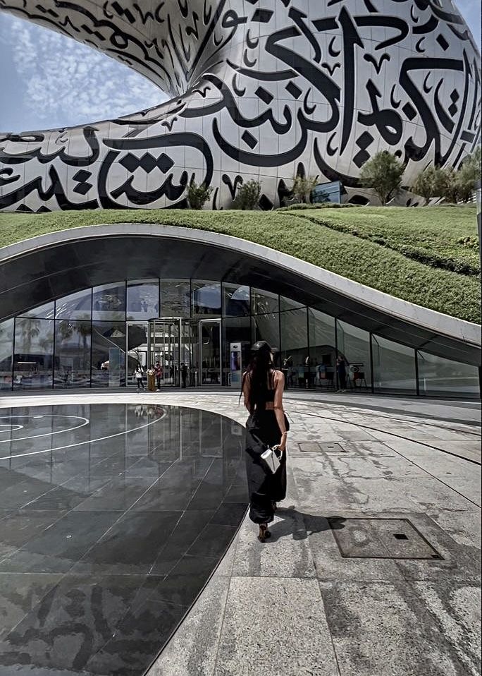 a woman standing in front of a building with arabic writing on it's side