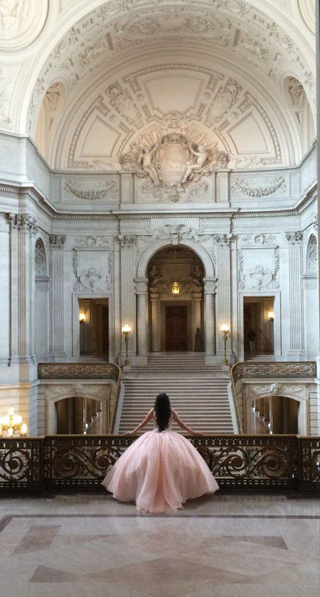 a woman in a pink dress is sitting on the stairs