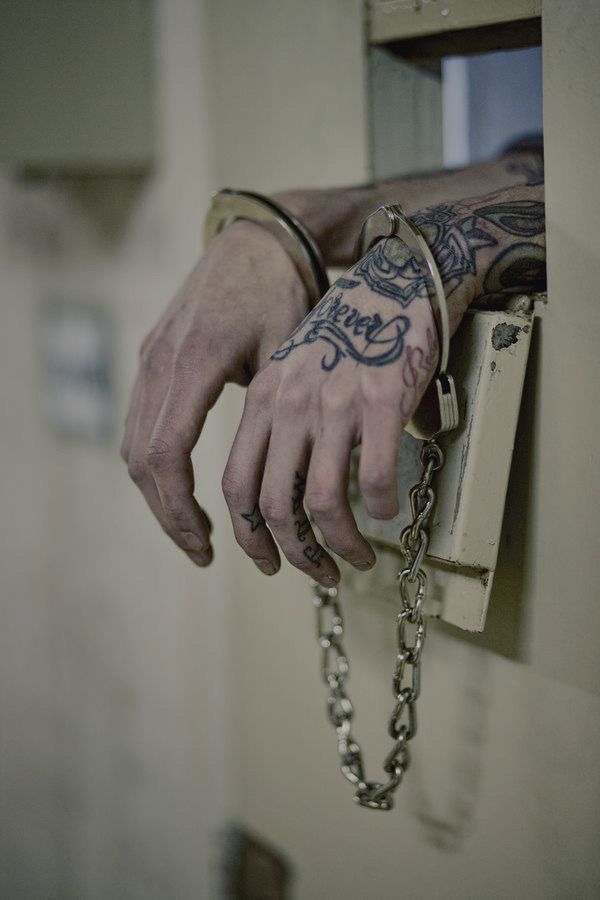 a man with tattoos on his arm holding onto a chain attached to a door lock