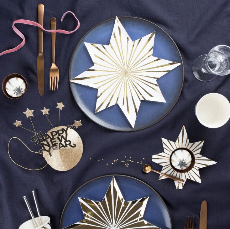 the table is set with plates, silverware and other holiday decorations on it's blue cloth