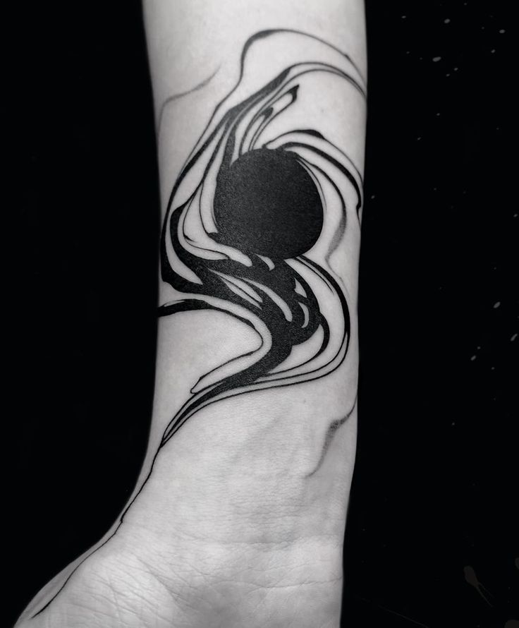 a black and white tattoo design on the left arm, with an abstract wave coming out of it