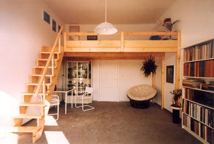 a loft bed with stairs and bookshelves in the corner next to a living room