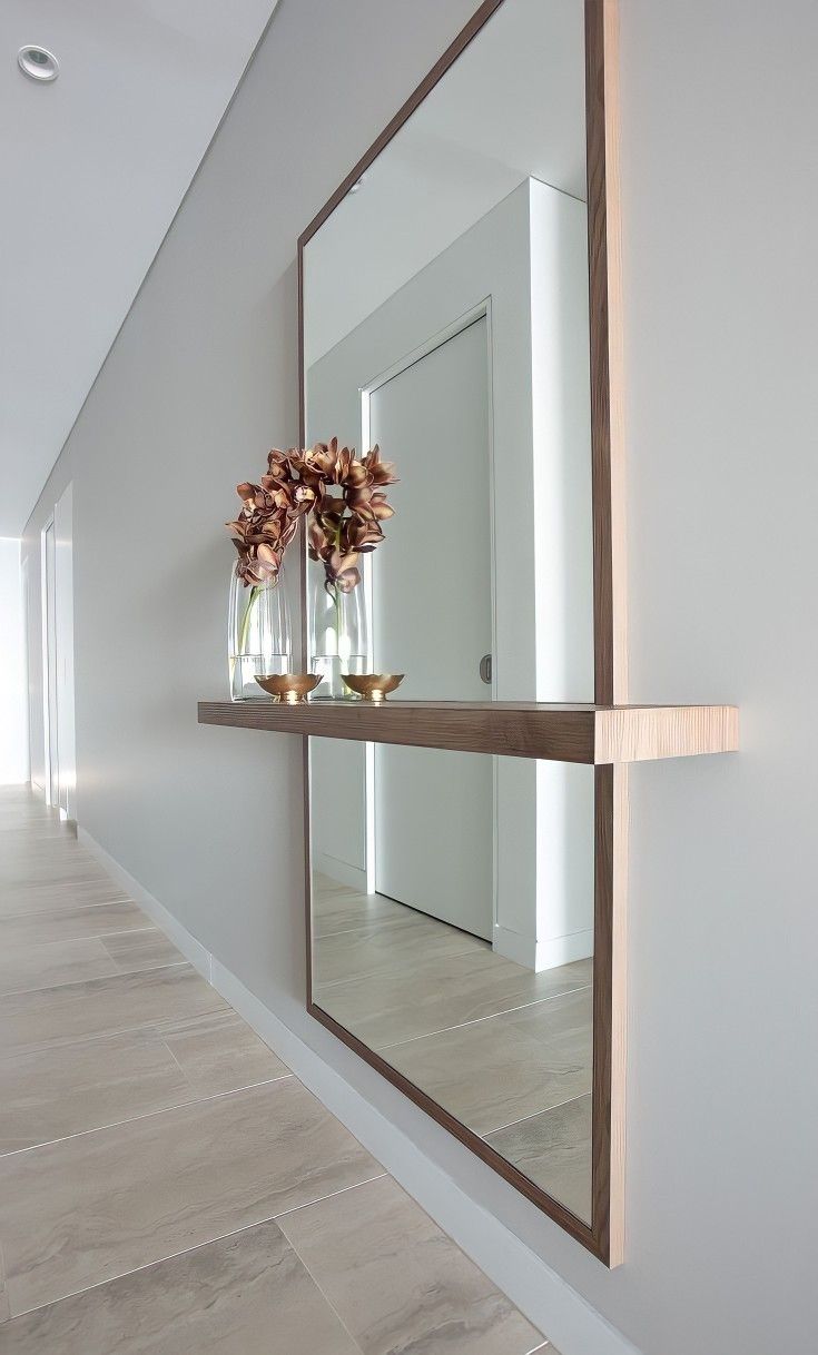 two vases with flowers are sitting on a shelf in front of a large mirror