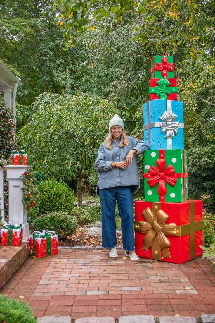 a woman standing next to a large stack of presents