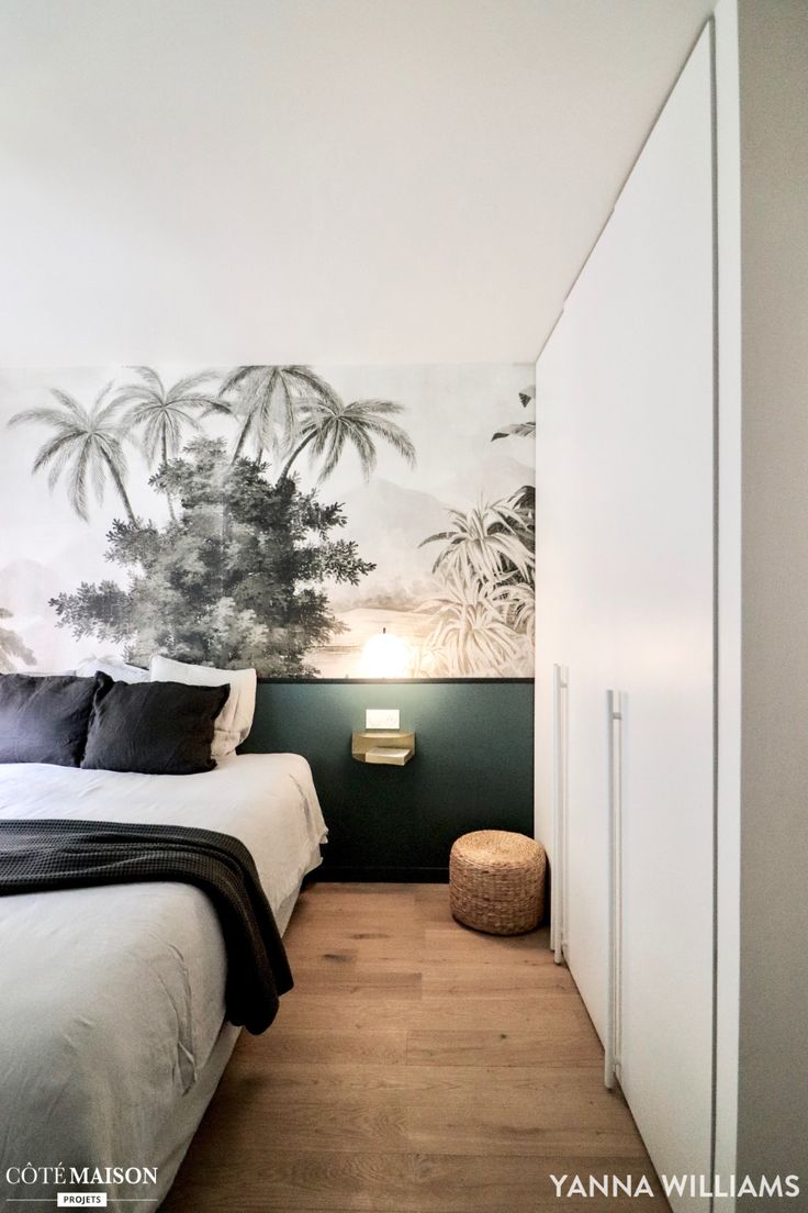 a white bed sitting in a bedroom next to a wall with palm trees on it