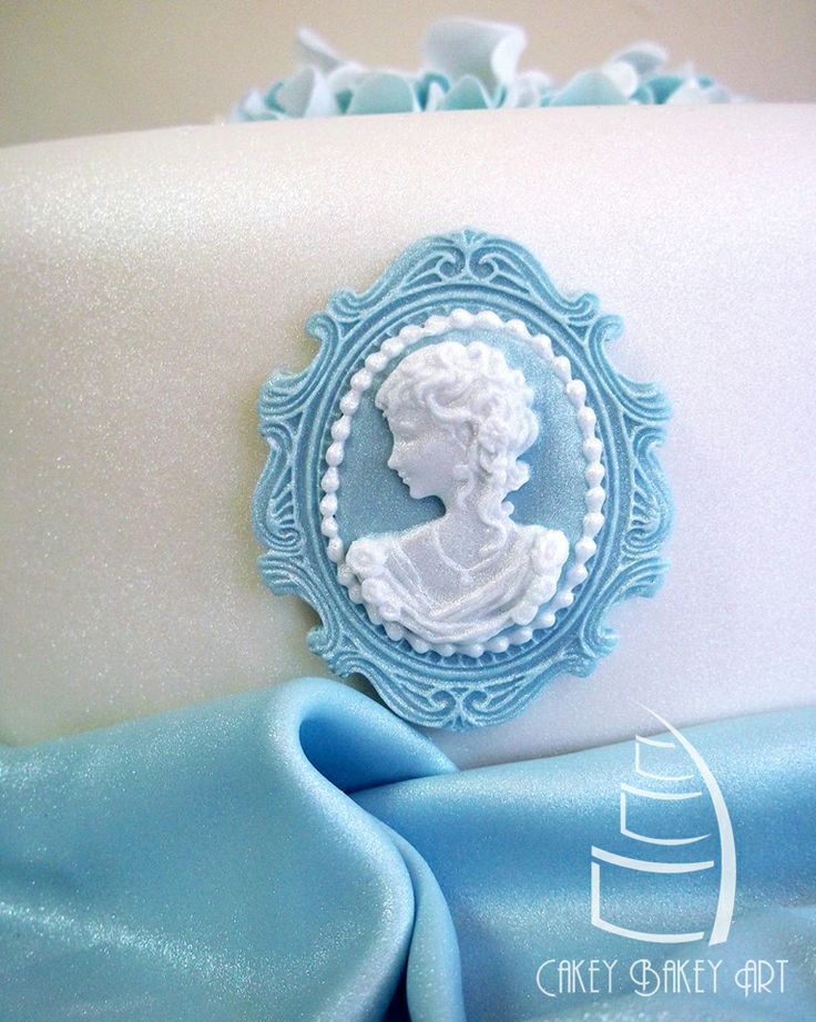 a blue and white cake with a lady's profile in the center on it