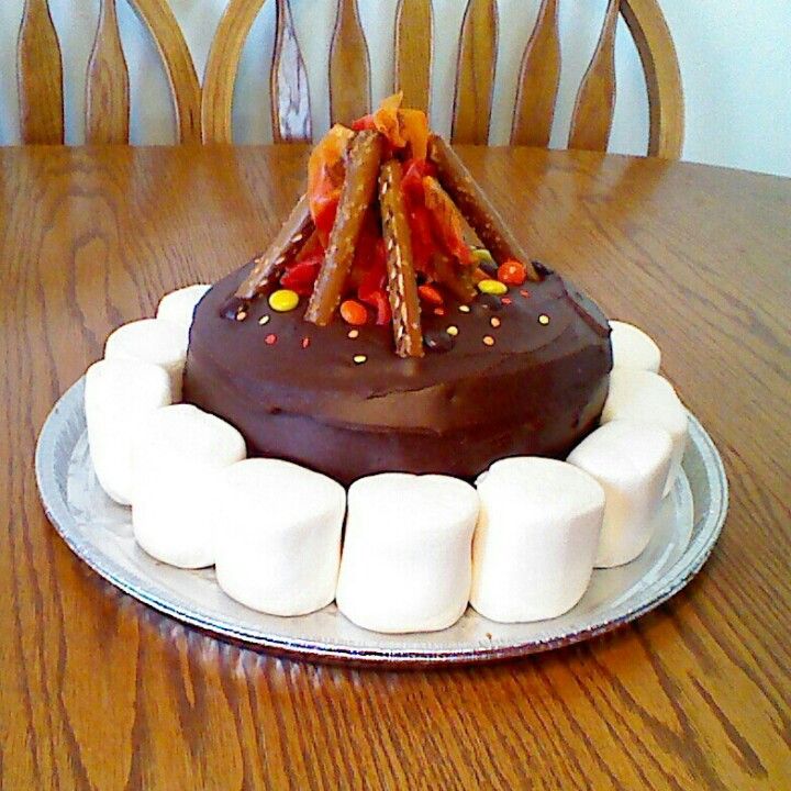 a chocolate cake with marshmallows and candies on top sitting on a table