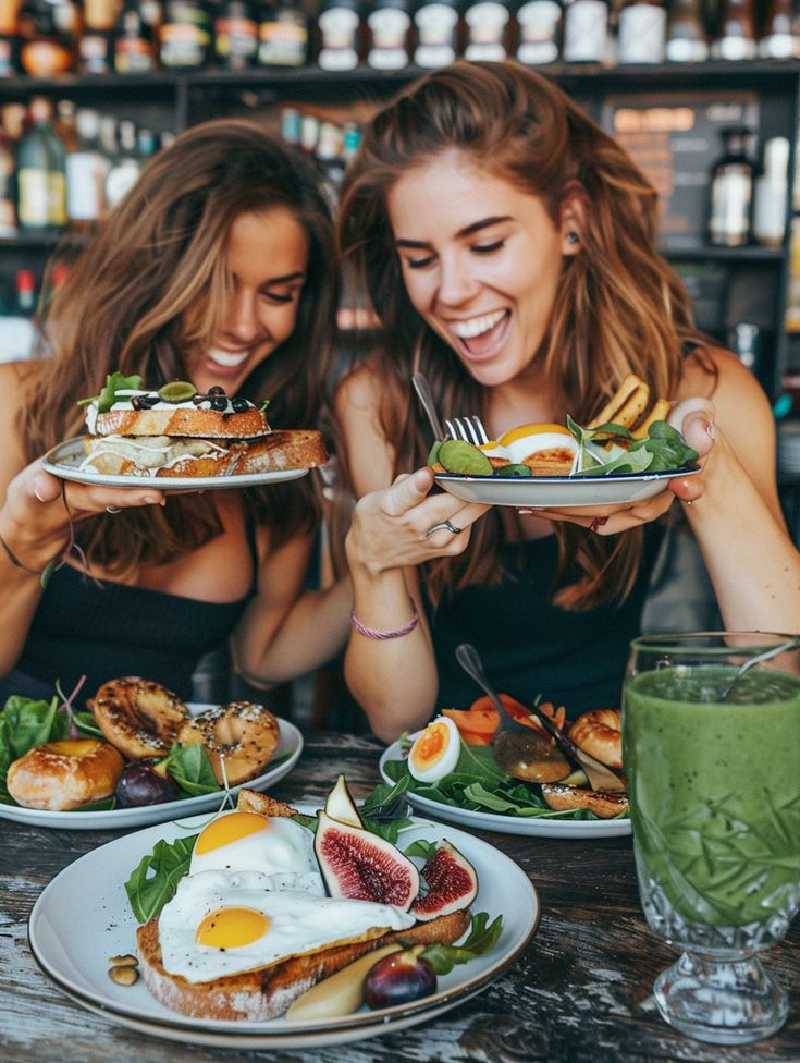 two women sitting at a table with plates of food