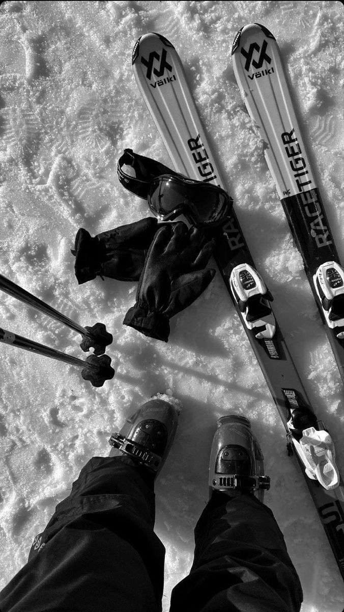 two pairs of skis sitting in the snow next to one person's feet