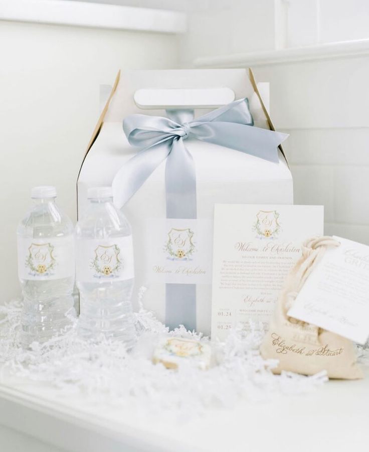 a white gift box with blue ribbon and some items on it sitting on a table