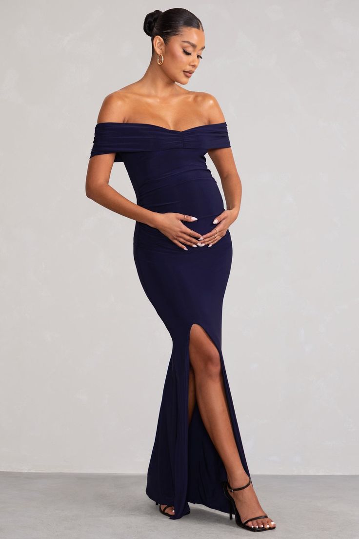 a pregnant woman in a blue gown posing for the camera with her hands on her belly