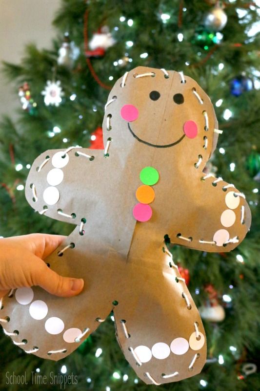 a hand holding up a paper ginger ornament in front of a christmas tree