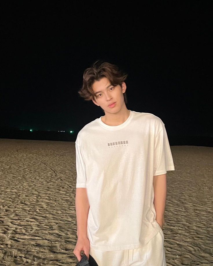 a young man standing on top of a sandy beach