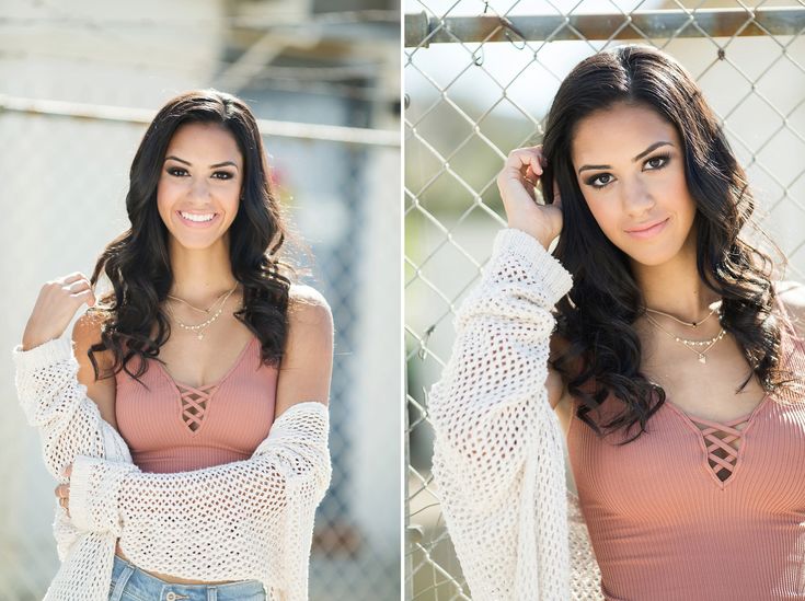 a beautiful young woman posing in front of a chain link fence with her arms behind her head