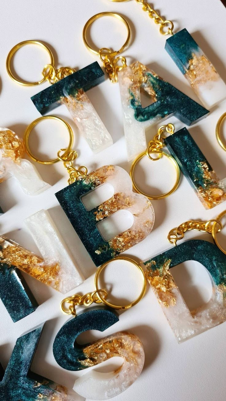 the letters are made out of gold and green marbles, with golden chains hanging from them