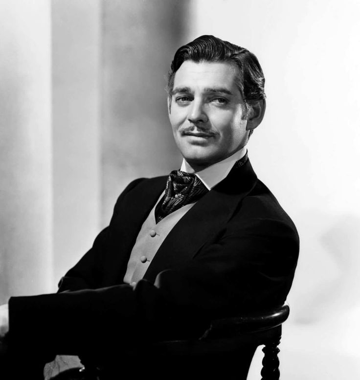 a man sitting in a chair with his arms crossed and wearing a suit over the top