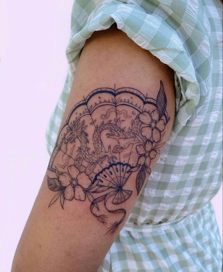 a woman's arm with a tattoo on it that has flowers and an umbrella