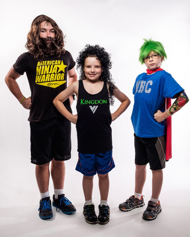 three young children standing next to each other in front of a white background wearing matching shirts and shorts