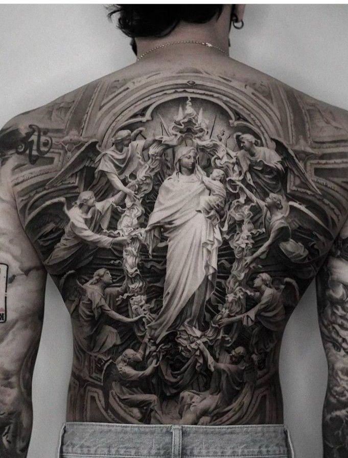 the back of a man's body with many tattoos on his chest and arms