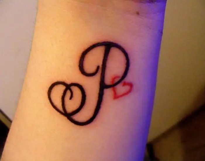 a small tattoo on the wrist of a woman's arm that reads p and has hearts in it