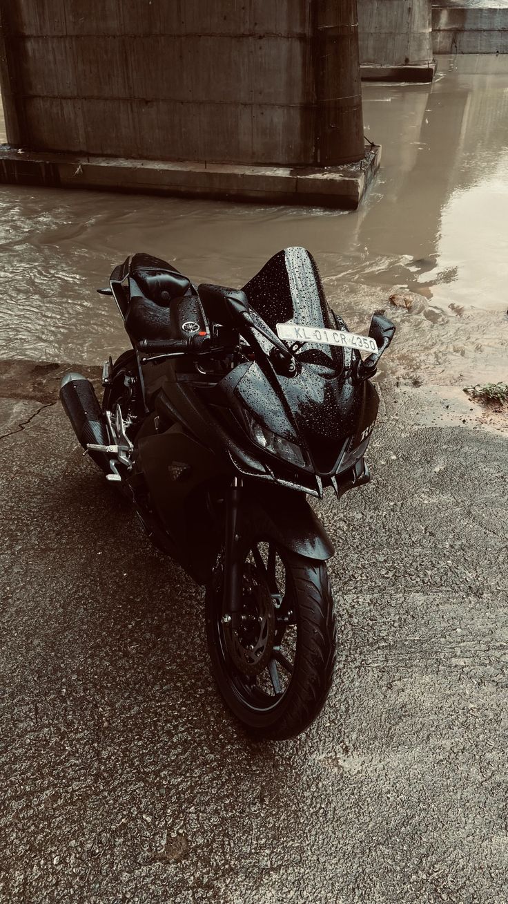 a black motorcycle parked in front of a bridge