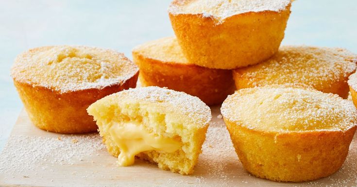 several cupcakes on a cutting board with powdered sugar over them and one cut in half