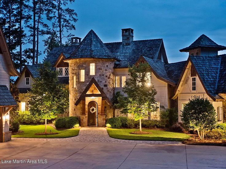 a large house with lots of windows and lights on it's front yard at night