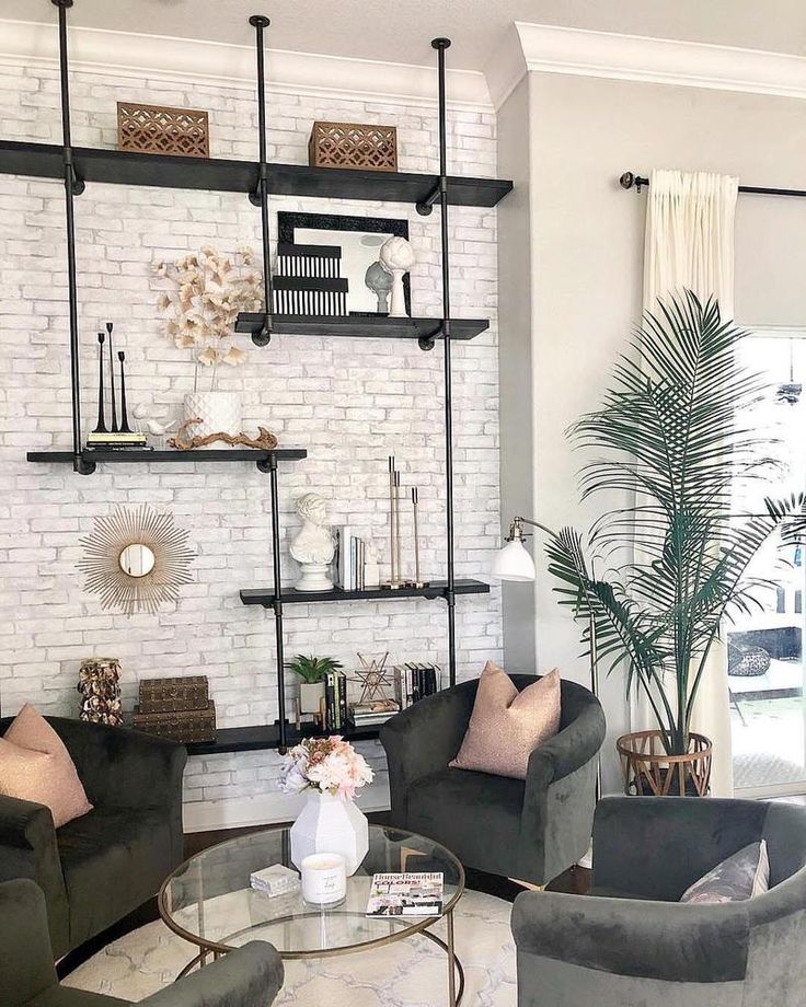 a living room with two couches and a coffee table in front of a white brick wall