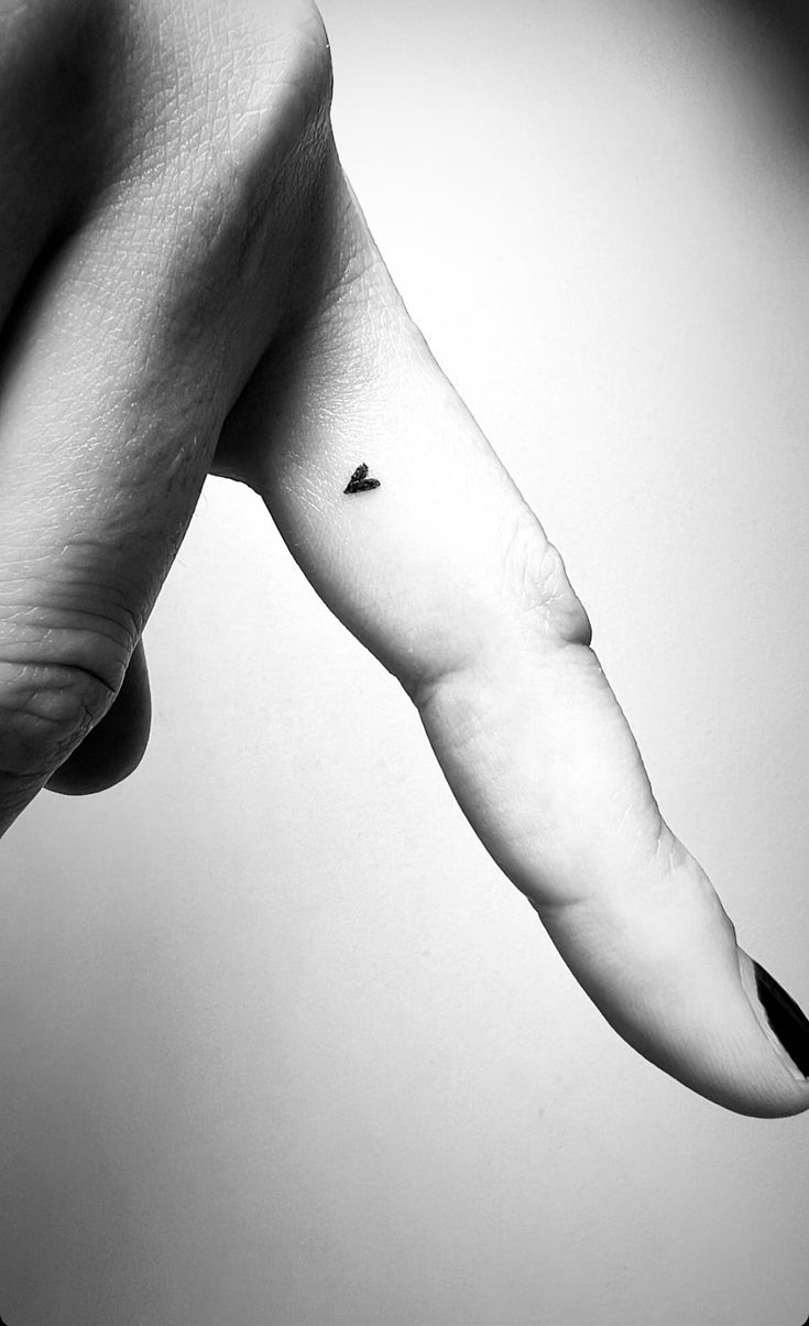 a black and white photo of a person's arm with a small tattoo on it