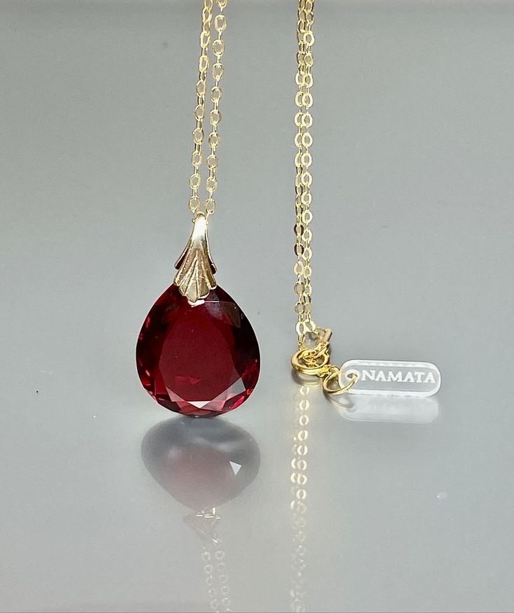 This pendant necklace showcases a gorgeous sparkly ruby pendant with a flawless, deep wine-red teardrop shape. The pendant exudes a captivating depth, reflecting light beautifully. It is gracefully strung on either a 14K gold-filled or Sterling Silver chain, offering versatility for layering with other necklaces or making a striking statement when worn alone. This necklace is truly a stunning beauty, radiating elegance and charm. Your description effectively conveys its allure and versatility. * Formal Drop Ruby Necklaces, Formal Ruby Drop Necklace, Fine Jewelry Ruby Drop Necklaces, Fine Jewelry Ruby Drop Necklace, Red Gemstone Pear-shaped Necklace, Red Briolette Necklace For Formal Occasions, Red Pear-shaped Necklace For Gift, Red Pear-shaped Gemstone Necklace, Ruby Teardrop Pendant Necklace