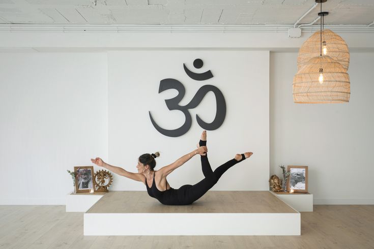 a woman is doing yoga in front of a wall with an om sign on it