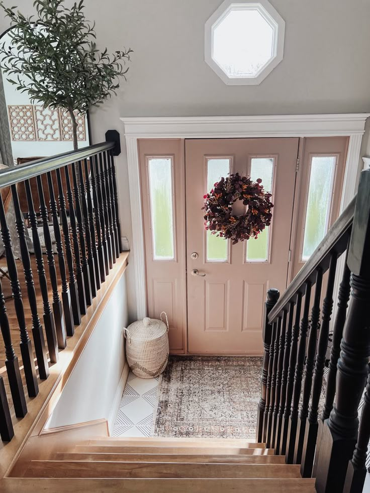 an entryway with stairs and a wreath on the door